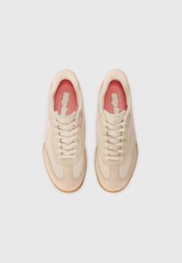 Beige athletic shoes with pink accents, mesh and suede material, round toe, lace closure, and a gum rubber outsole.