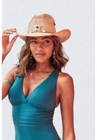 Teal ensfittet badedrakt med v-utringning, rynkedetaljer og en stråhatt i cowboy-stil med blomsteraksent og skjell.