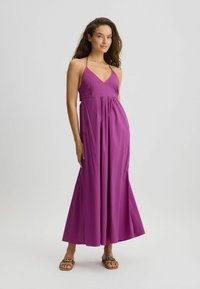 Maxi dress in vibrant magenta, featuring a V-neckline, adjustable straps, and flowing fabric with a pleated waist for added movement.
