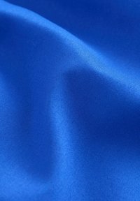 Tissu bleu vif avec une texture lisse, présentant des variations subtiles de brillance et de profondeur, plié pour mettre en valeur sa qualité douce et fluide.