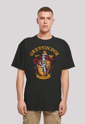 Svart bomull T-skjorte med Gryffindor-våpen i rød, gul og hvit, med løve, krone detaljer, og fet tekst over og under emblem.