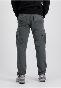 Dark gray cargo pants featuring multiple pockets, a relaxed fit, and a smooth fabric texture, paired with gray sneakers.
