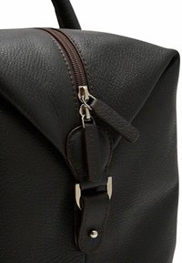 Mörkbrun läderryggsäck med en texturerad yta, utrustad med en framträdande dragkedja och silverfärgade detaljer.