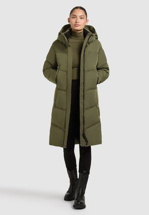 Olive green puffer coat with a hood, zip closure, and side pockets. Features a quilted design and is worn over a black turtleneck and pants.