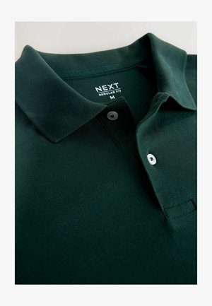 Polo de color verde oscuro hecho de algodón texturizado. Cuenta con un cuello clásico, una tapeta de dos botones y una etiqueta tejida de la marca en el cuello.