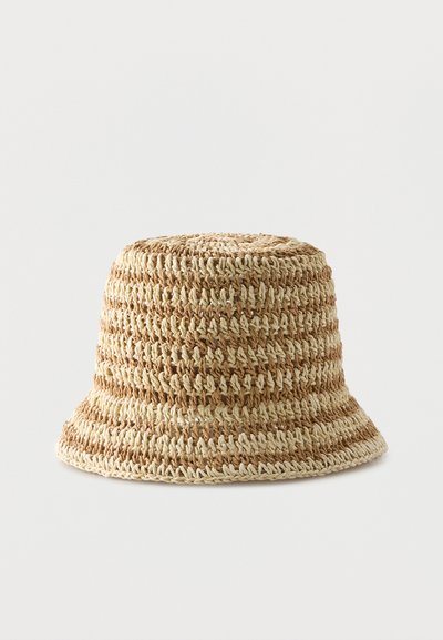 Φυσικό καφέ και μπεζ καπέλο τύπου bucket, πλεκτό με βελονάκι, με φαρδιά, ελαφρώς φουντωτή γείσο, παρουσιάζεται σε απλό λευκό φόντο.