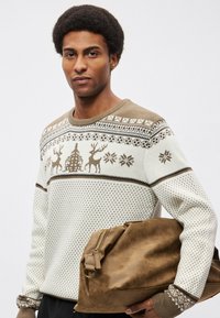 Πλεκτό πουλόβερ σε κρεμ με καφέ λεπτομέρειες, με σχέδιο ελάφι και δέντρο, σε συνδυασμό με καφέ τσάντα με υφή. Λεπτομερές σχέδιο στις μανσέτες.