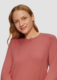 Leichter, langärmeliger Pullover mit Rundhalsausschnitt in einem staubigen Rosaton, der eine glatte Textur und dezente Steppnähte entlang der Nähte aufweist.