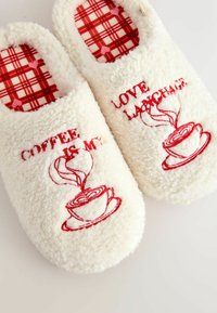 Biele nadýchané papuče s červenou výšivkou. Na vonkajšej strane vzor šálky kávy a nápis „COFFEE IS MY LOVE LANGUAGE“. Červené kárované vnútro.
