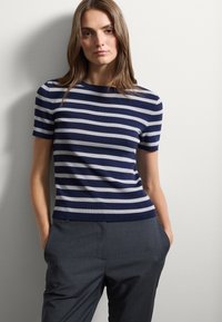 Top a maniche corte a righe blu navy e grigio chiaro; scollatura rotonda, design aderente, abbinato a pantaloni grigi su misura.