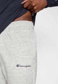 Γκρι βαμβακερά joggers με υφή, με κεντητό λογότυπο "Champion" σε σκούρο μπλε στο αριστερό μηρό και ελαστική μέση.