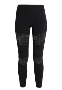 Leggings noires avec des panneaux en dentelle noire intricats au niveau des genoux, dotés d'un tissu lisse et extensible et d'une coupe ajustée.