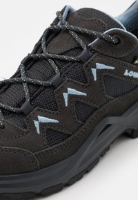 Scarpa da trekking nera con tomaia in suede testurizzato e rete, dettagli blu e una suola in gomma robusta con un motivo di battistrada pronunciato.