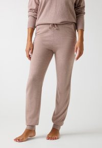 Pantalones de lounge suaves y ligeros en un tono rosa claro, con un ajuste relajado, puños acanalados, cintura con cordón y una textura suave, diseñados para la comodidad.