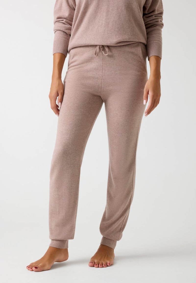Pantalones de lounge suaves y ligeros en un tono rosa claro, con un ajuste relajado, puños acanalados, cintura con cordón y una textura suave, diseñados para la comodidad.