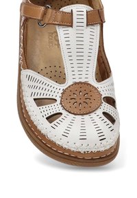 Sandal de cuero blanco con acentos marrones, que presenta diseños recortados, perforaciones y un detalle de borde cosido. Correa ajustable con hebilla.