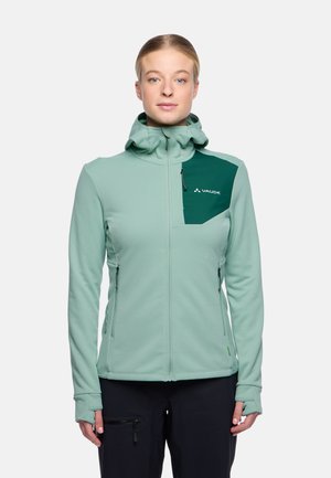 Mintgroene softshell jas met een capuchon, voorzien van een donkergroen accentzakje en ritsen aan de zijkanten, gemaakt van flexibel materiaal.