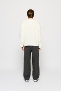 White long-sleeve top with a relaxed fit, paired with dark gray wide-leg pants. Soft fabric, simple design, with subtle stitching details.