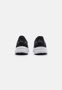 Black athletic shoes with a mesh upper, white midsole, and black outsole. Features include reflective accents and a rounded shape.