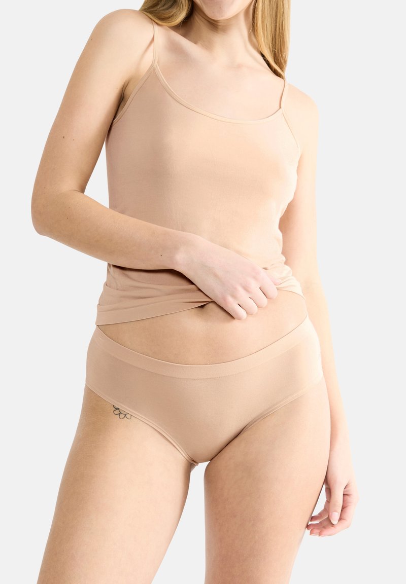 Ensemble de haut en camisole beige clair et de culottes assorties en tissu doux. Le haut présente des bretelles fines, tandis que la culotte a une ceinture sans couture.