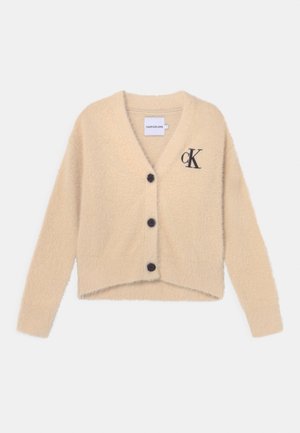 Beżowy, miękki kardigan z czarnymi guzikami, dekoltem w serek, długimi rękawami oraz czarnym logo "cK" na lewej piersi.