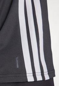 Czarna sportowa koszulka z trzema białymi pionowymi paskami i metką "climacool". Materiał wydaje się być gładki, z dopasowanym krojem.