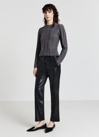 Grauer gestrickter Pullover mit strukturiertem Muster und Peplumsaum. Kombiniert mit schwarzen Lederhosen und spitzen schwarzen Ballerinas. Minimalistisches Design.