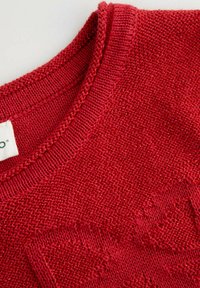 Czerwony sweter dzianinowy z fakturowanym wzorem, prążkowanym kołnierzem i metką umieszczoną w lewym górnym rogu. Tkanina wygląda na miękką i ciepłą.