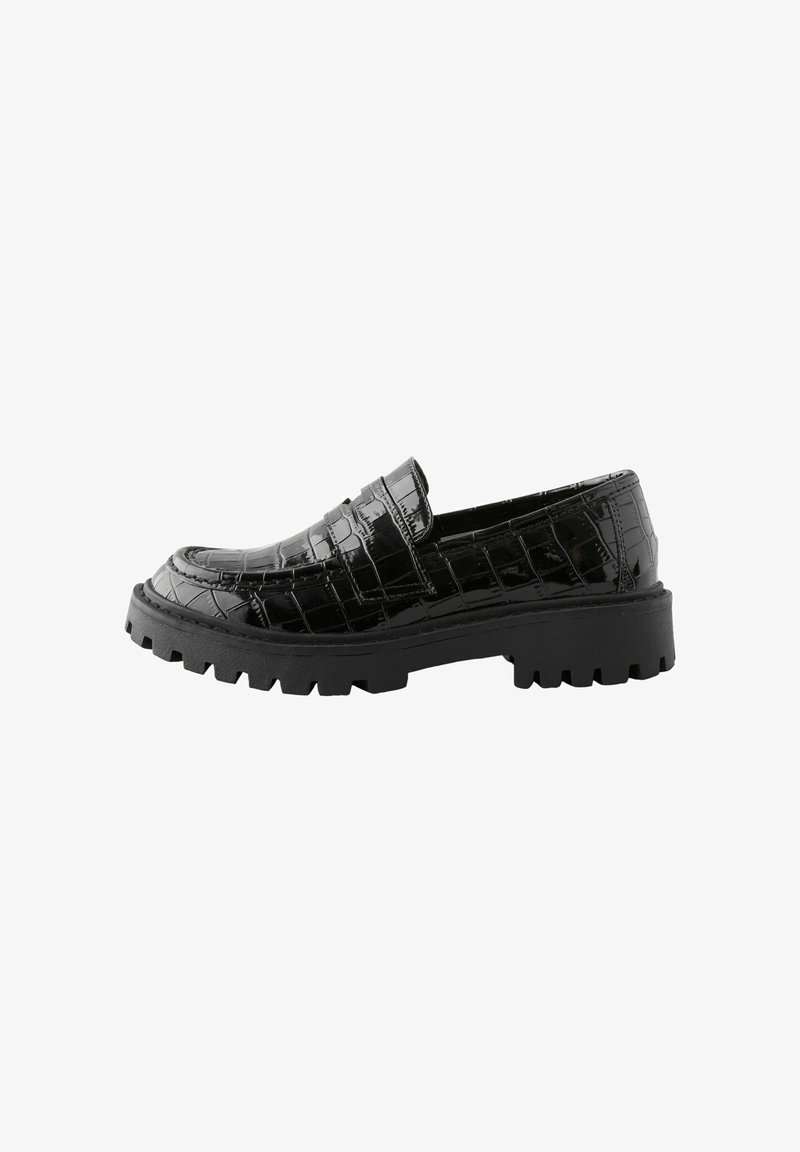 Mocassin noir brillant en cuir synthétique effet crocodile avec semelle crantée épaisse et petit talon, style slip-on avec bride décorative à l'avant.