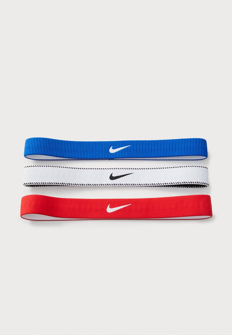 Trois bandeaux Nike affichés : le haut en bleu avec un logo blanc, le milieu en blanc avec un logo noir et des détails de couture, le bas en rouge avec un logo blanc.