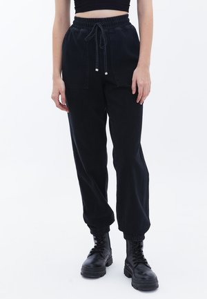 Pantaloni jogger in denim nero con vita elastica e coulisse, dotati di polsini elastici e due tasche frontali. Tessuto liscio.