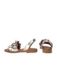 Metalliske guld sandaler har en blomsterdekoration, et slingback-design og en brun sål med syninger. Flad, åbentået stil.