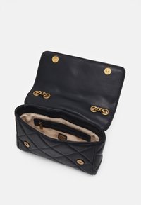 Musta tikattu nahkalaukku, jossa on kultainen ketjusomiste ja kaksi magneettista nepparia. Sisäpuolella on beigevuori ja vetoketjutasku.