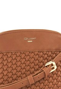 Tan leather handbag featuring woven texture on the lower half, smooth upper section, gold-tone hardware, and a branded logo.