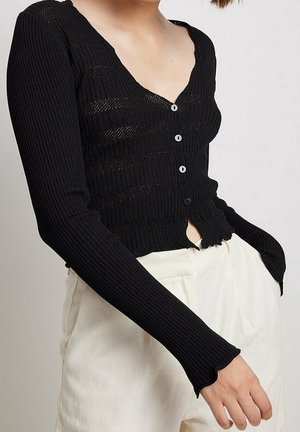 Cardigan noir à rayures, à manches longues, avec un col en V, six boutons et un ourlet festonné. Le tissu présente une apparence texturée et légère.