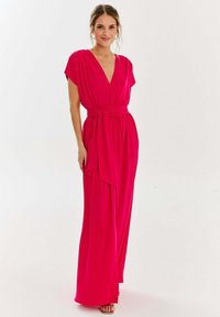 Różowa, krótko-sleeve sukienka maxi z dekoltem w serek i związanym w pasie. Wykonana z lekkiego materiału, charakteryzuje się swobodnymi liniami i luźnym krojem.