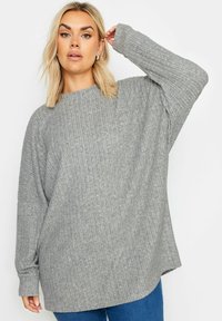 Grauer gerippter Oversized-Pullover mit langen Ärmeln und weitem Ausschnitt, der ein strukturiertes Strickmuster und eine entspannte Silhouette aufweist.