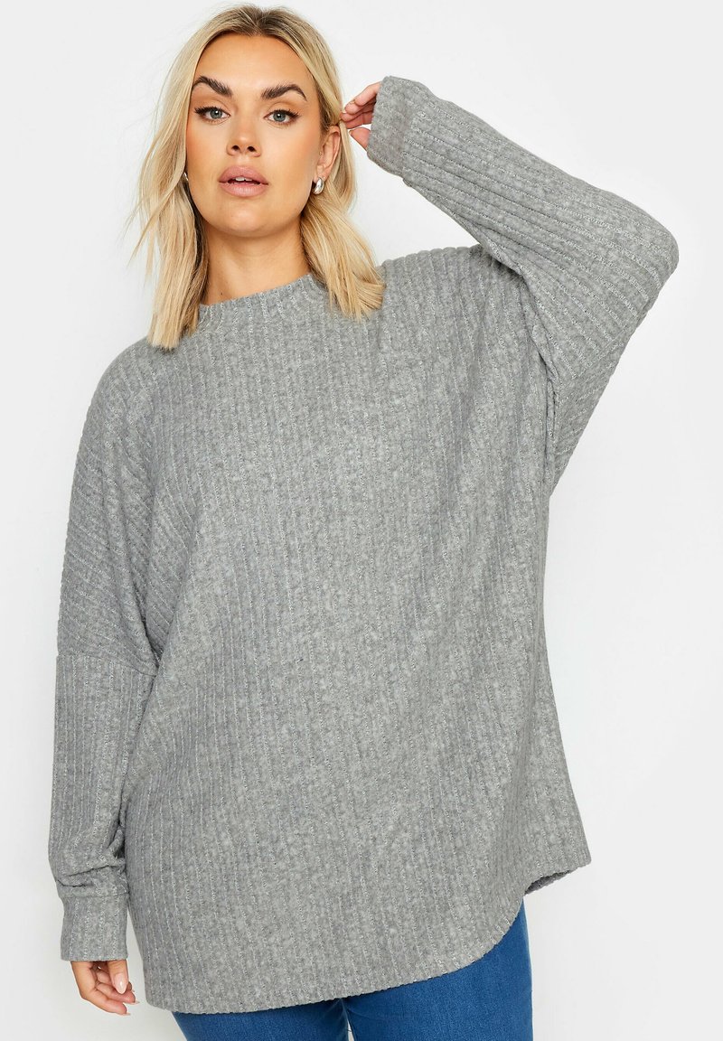 Grauer gerippter Oversized-Pullover mit langen Ärmeln und weitem Ausschnitt, der ein strukturiertes Strickmuster und eine entspannte Silhouette aufweist.