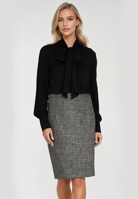 Czarna bluzka z długim rękawem z detalem w postaci kokardy przy szyi, zestawiona z szaro-skalnym ołówkowym spodnicą o teksturowanym wykończeniu.