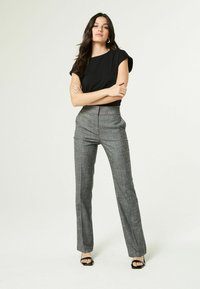 Zwarte korte mouwen top gecombineerd met hoog-waisted, grijs geruite broek; heeft een getailleerde pasvorm en een wijde broekspijp ontwerp. Zwarte hoge hakken sandalen maken de look compleet.