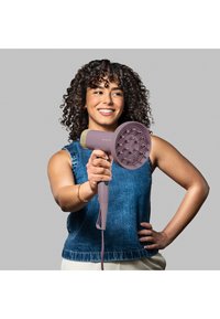 Hårføner i lys lilla med en teksturert rund dyse, med gullakenter. Håndtaket er utformet for ergonomisk grep med strømkabel festet.