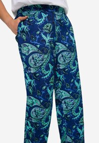 Pantaloni blu a fantasia con un design paisley nelle tonalità di verde e nero, dotati di una cintura elastica e tasche laterali.