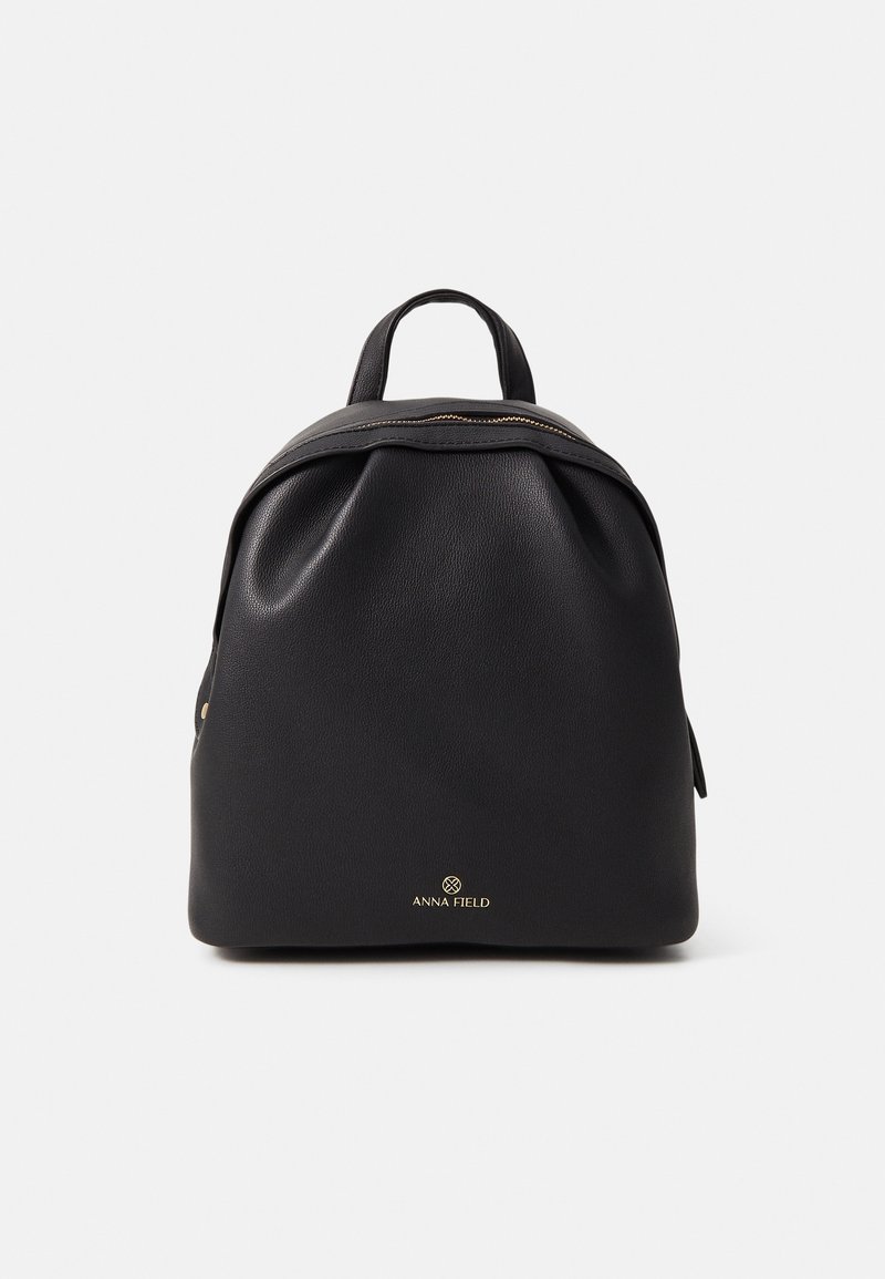 Zaino in pelle nera dalla forma tondeggiante, con dettagli della cerniera in oro e manico superiore. Presenta un logo dorato sul davanti.