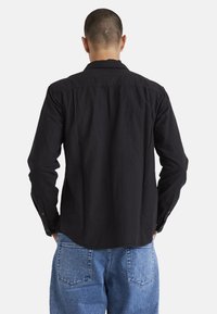Black long-sleeve shirt made of cotton with a button-down collar and cuffs. Features a straight hem and a smooth texture.