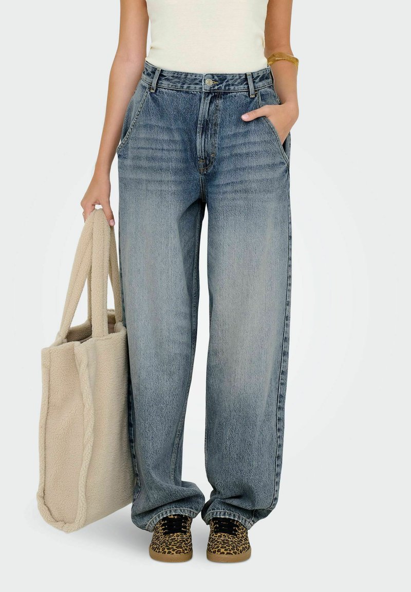 Vida jeans i ljusblå denim med vida ben, hög midja, framfickor och subtila blekningar. Kompletteras med en beige tote-väska och mönstrade skor.