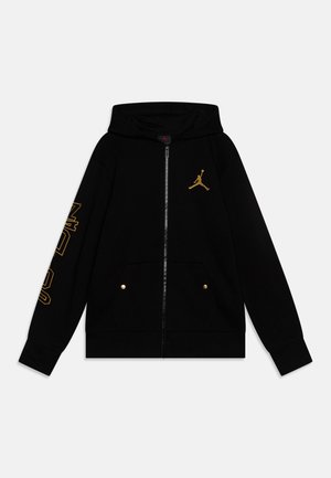 Czarna bluza z kapturem na zamek z złotym logo Jumpman na piersi, złotym napisem "Jordan" na rękawie, przednimi kieszeniami z złotymi zatrzaskami i kapturem.