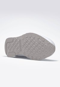 Reebok-Sneaker-Sohle mit einem strukturierten, hellgrauen Gummimaterial, das ein Wabenmuster aufweist, und einer in der Mitte eingeprägten Markenkennzeichnung.