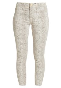 Jeans ajustados en un patrón de serpiente beige claro, con una superficie texturizada, bolsillos frontales y un cierre de botón metálico.
