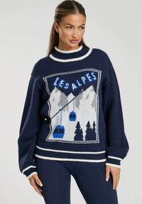Pull navy con un design grafico che rappresenta montagne e impianti di risalita. Orlo e bordo del collo a coste bianchi, realizzato in materiale morbido.