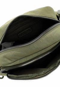 Borsa in tessuto verde con numerosi scomparti con zip. L'interno presenta una fodera liscia e un logo visibile sul tessuto. Cerniere in metallo robuste.